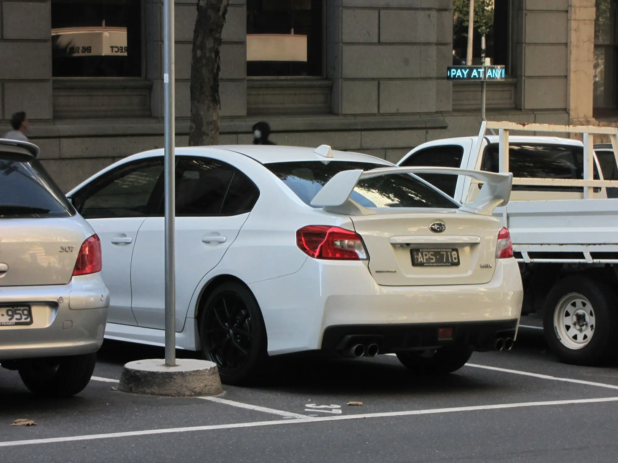 White sedan and a tray ute parked in an Australian city car park
