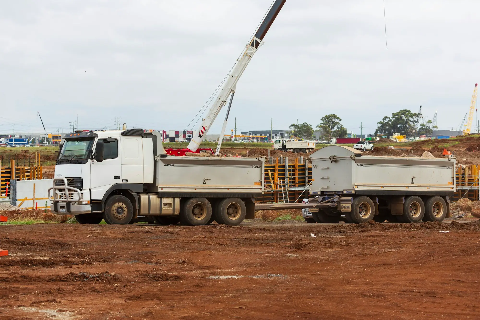 Tipper trucks and a crane on a red-dirt Australian building site
