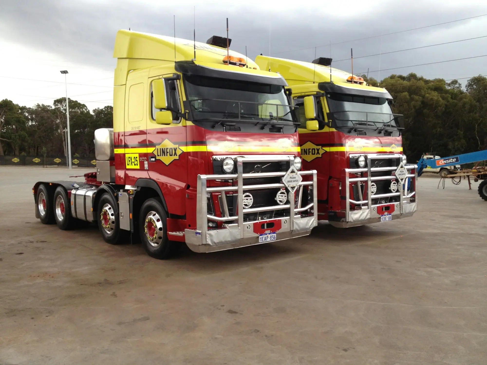 Two prime movers with bull bars parked side by side in a transport yard