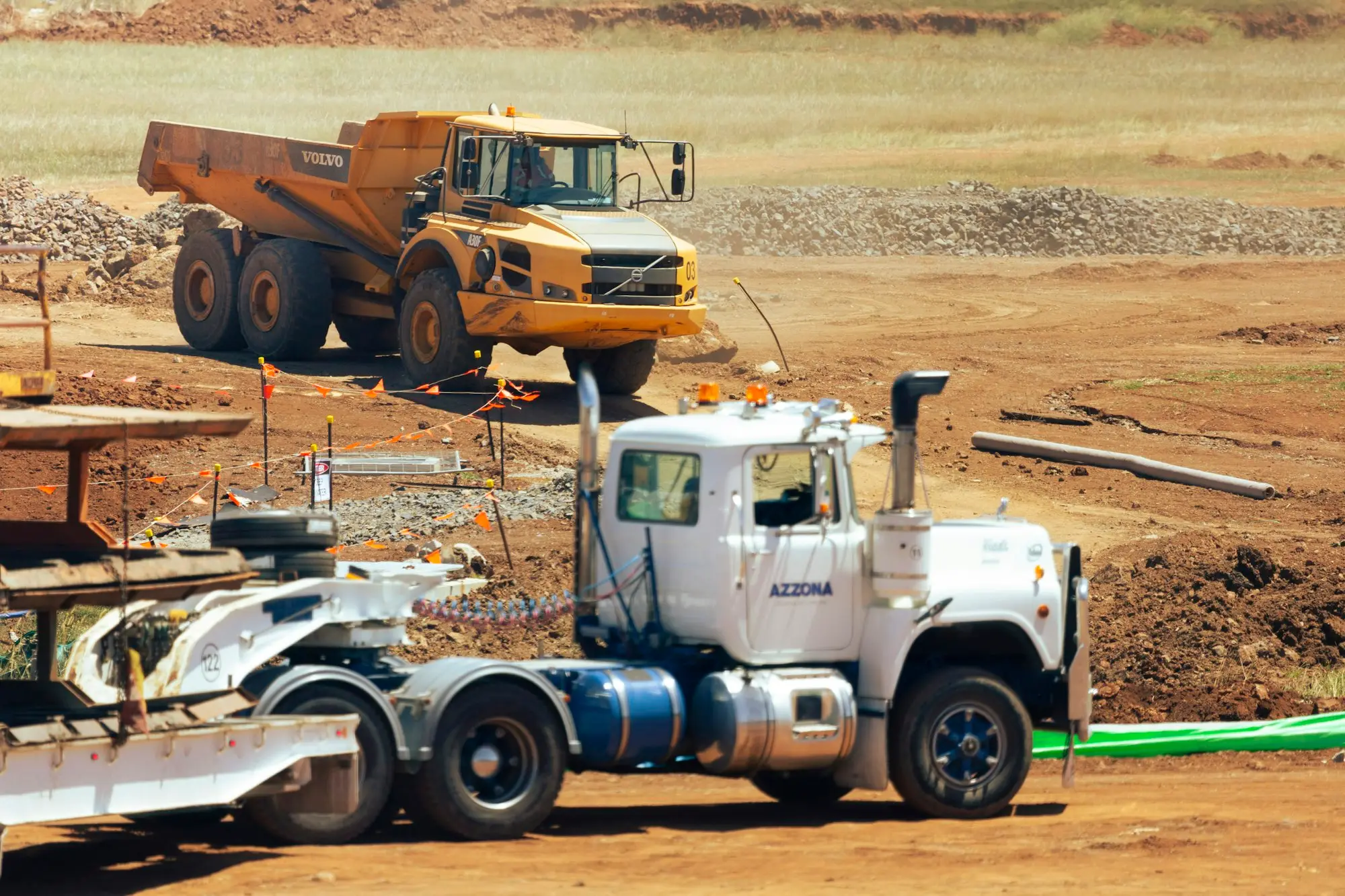 Prime mover and dump trucks lined up in a business yard on red earth