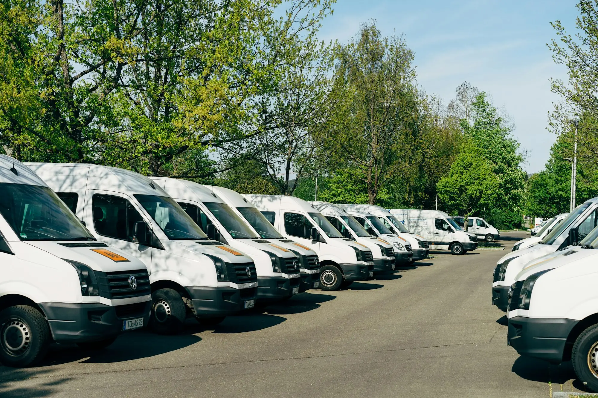 Row of white panel vans parked nose-out at a business depot ready for the day's deliveries